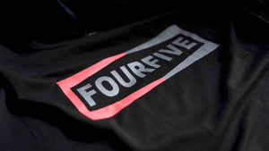 A Fourfive 45 black Champ t shirt close up of the Fourfive champ graphics at a 45 degree angle with dramatic lighting.