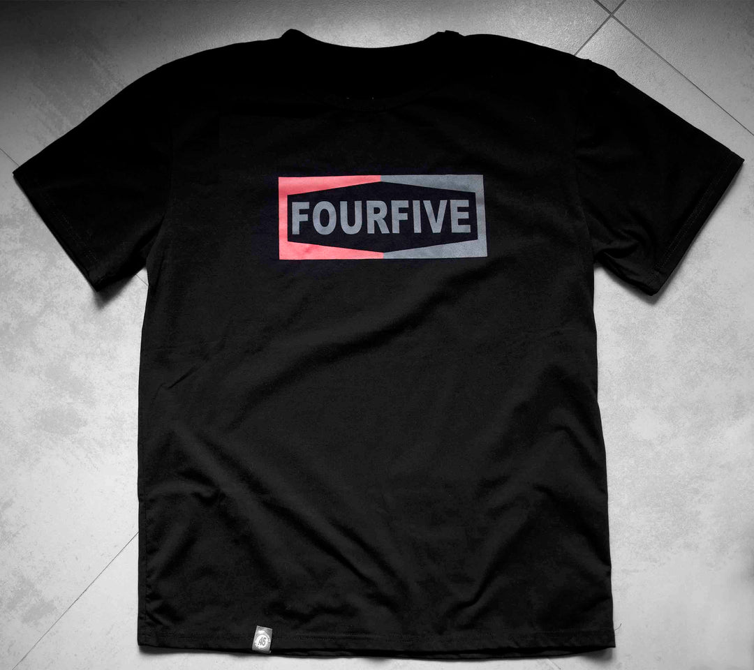 A Fourfive 45 black Champ t shirt with the Fourfive champ graphics sitting on a concrete back ground.