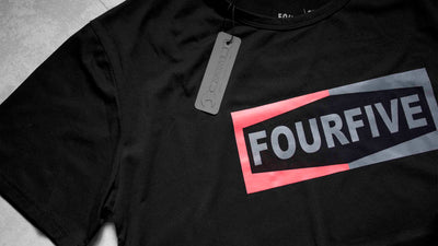 A Fourfive 45 black Champ T shirt zoomed in showing parts of the Fourfive champ graphics and product tag on the black t shirt.