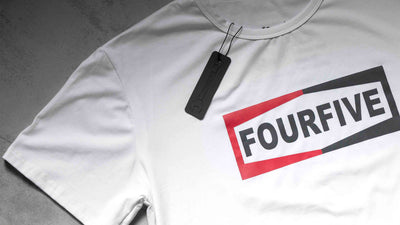 A Fourfive 45 white Champ T shirt zoomed in showing parts of the Fourfive champ graphics and product tag on the black t shirt.
