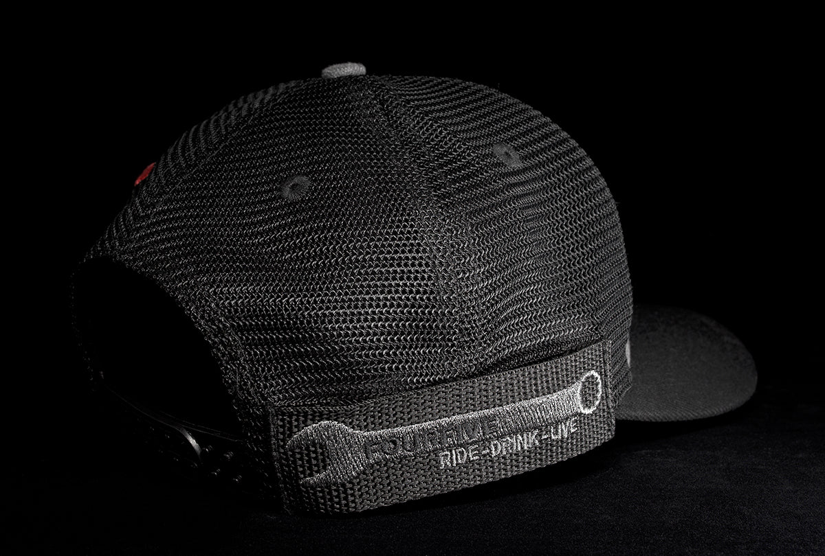 A Fourfive 45 Flat Tracker hat with a curved brim in a grey cotton material front with its 45 degree back right view showing the hat holster mount and its embroidery detail black mesh back and a snapback strap in dramatic lighting with black background.   Built to fit normal and big heads.