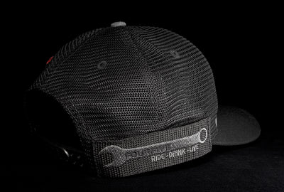 A Fourfive 45 Flat Tracker hat with a curved brim in a grey cotton material front with its 45 degree back right view showing the hat holster mount and its embroidery detail black mesh back and a snapback strap in dramatic lighting with black background.   Built to fit normal and big heads.
