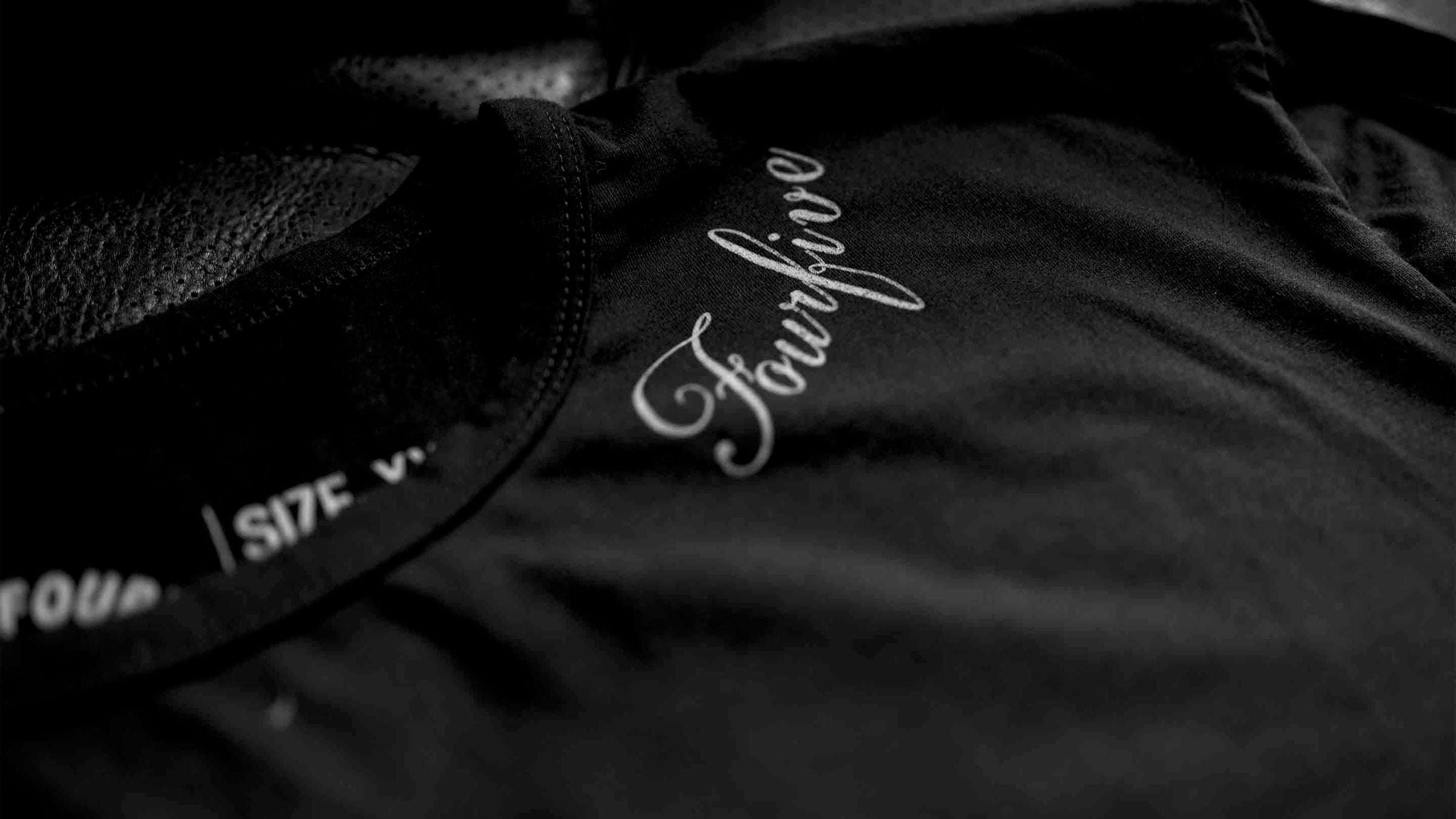 A Fourfive 45 black tattoo t shirt close up of the Fourfive tattoo graphics along the left side of the collar at a 45 degree angle with dramatic lighting.
