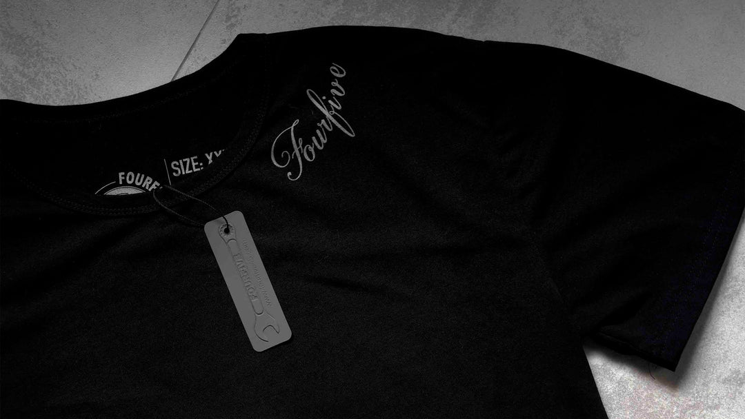 A Fourfive 45 black tattoo T shirt zoomed in showing parts of the Fourfive tattoo graphics around the left side of the collar and product tag on the black t shirt.