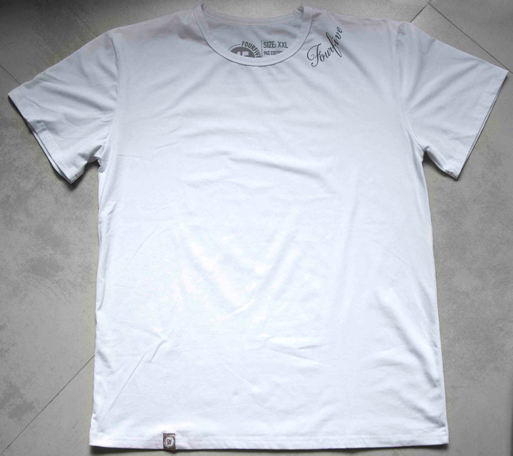A Fourfive 45 white tattoo t shirt with the Fourfive tattoo graphics on the left side of the collar sitting on a concrete back ground.