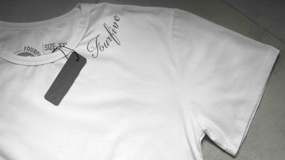 A Fourfive 45 white tattoo T shirt zoomed in showing parts of the Fourfive tattoo graphics around the left side of the collar and product tag on the black t shirt.