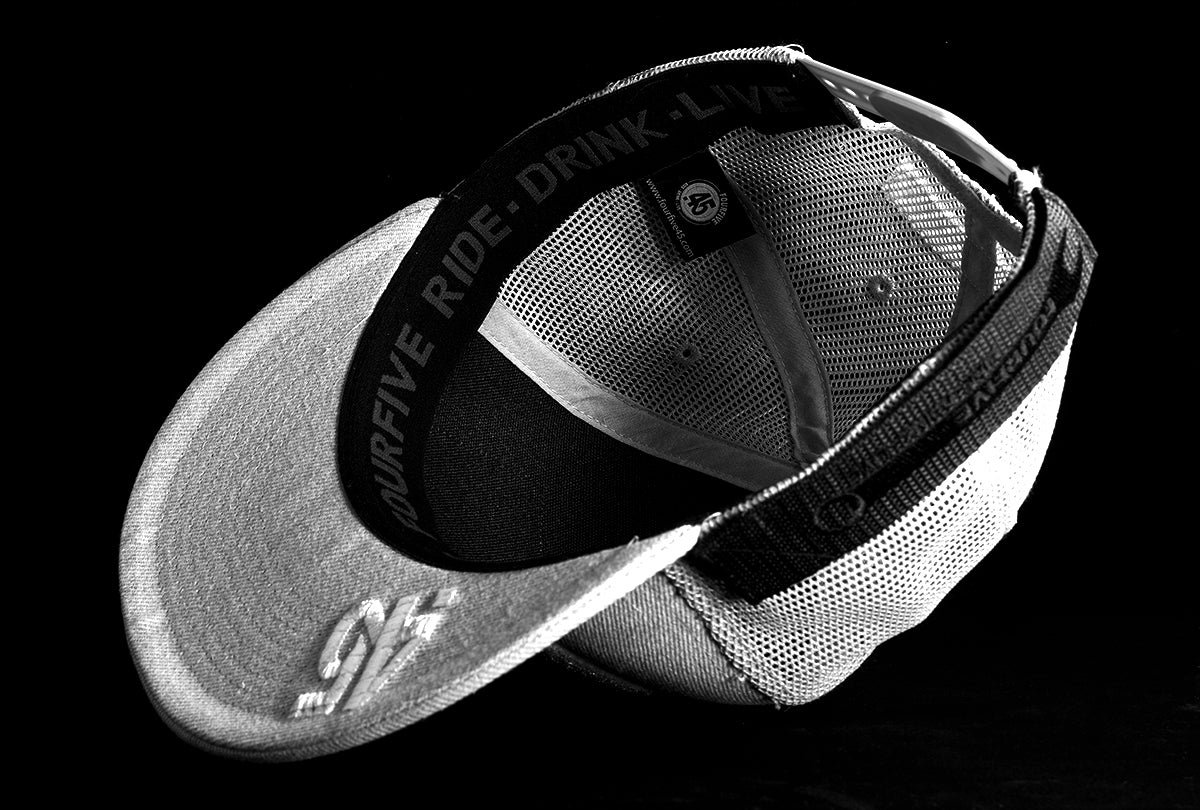 A Fourfive 45 Customizer hat snow edition with flat brim light grey cotton front and white velcro logo detail for customising and light grey mesh back  flipped over showing the 45 logo embroidery detail on the bottom of the brim and the ride drink live embroidery detail around the sweat band on the inside of the hat.  Built to fit normal and big heads.